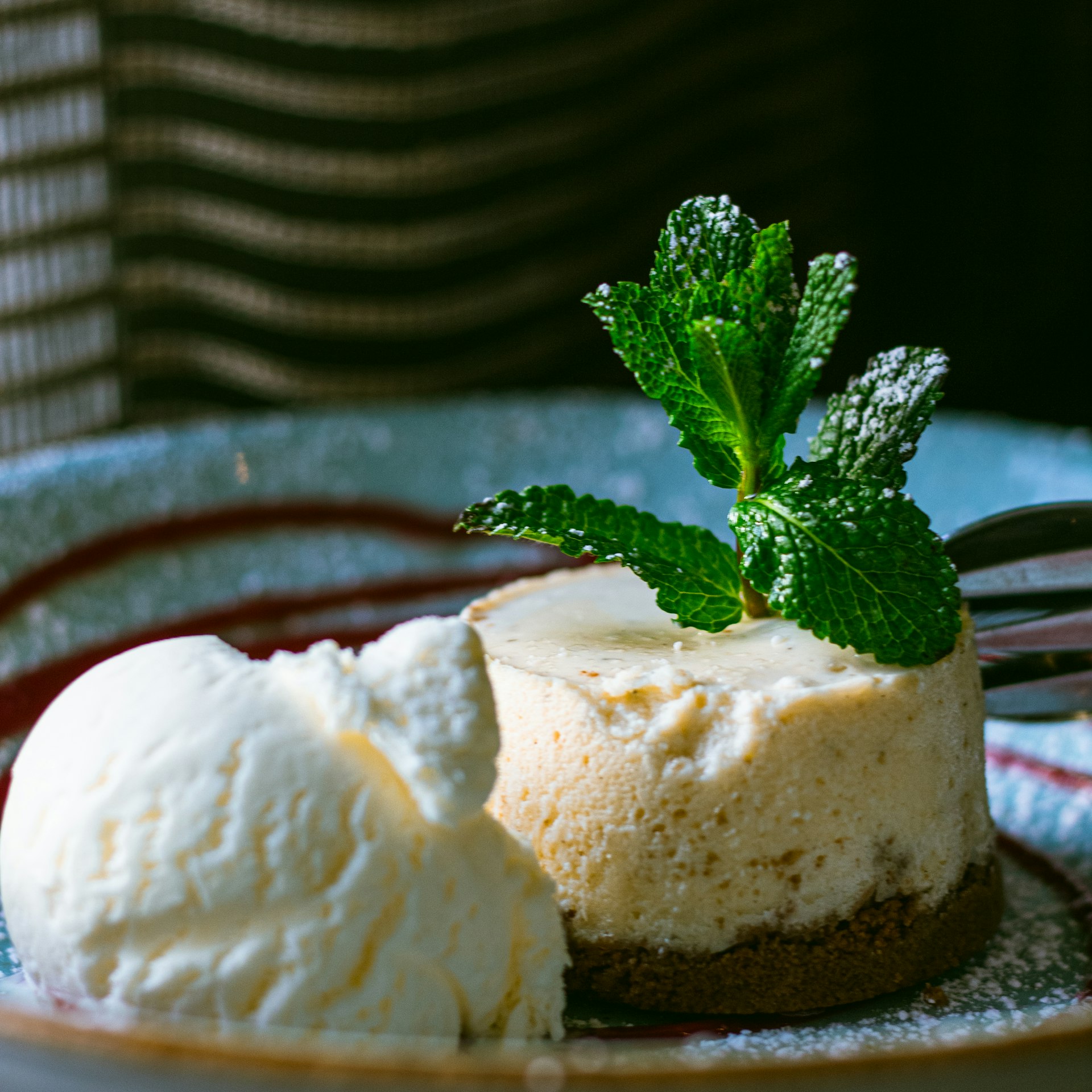 a plate with a piece of cheesecake and a scoop of ice cream